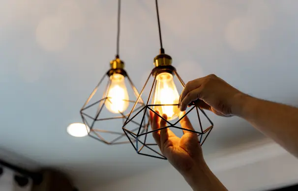 1745291745946_1745228917039_GettyImages-894471 1 (9) Hands adjusting modern pendant light bulbs.